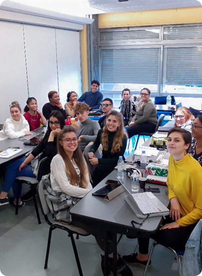 étudiants assistant à un cours on y voit une vingtaine d'étudiants souriants face à la caméra, assis à leur bureau