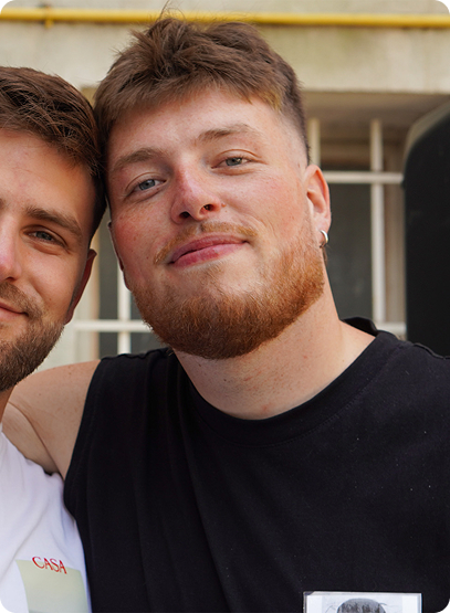 Deux étudiants sourient face à la caméra autour d'une accolade