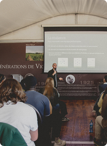 Un intervenant prenant la parole lors d'un séminaire au sujet de la préparation mentale. Une salle remplie d'étudiants le regardent alors qu'il prend la parole.