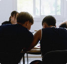 Plusieurs sportifs sont en classe, au premier plan, on y vit deux joueurs de dos en train de discuter autour d'une table de cours