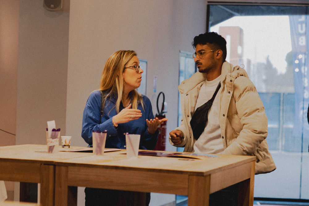 Photographie de deux pesonnes discutant autour d'une table, une femme qui représente l'entreprise, et un homme qui représente le sportif de haut niveau